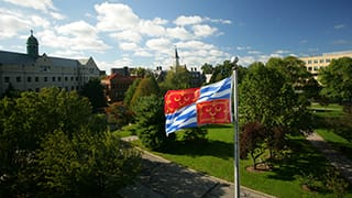 A photo of campus with the University flag.