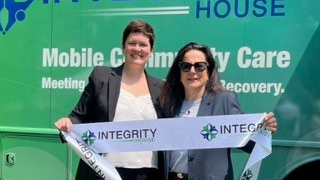 Image of Integrity House Project Director Katie Tracy and Associate Dean Kathleen Neville celebrated the ribbon cutting of the new mobile unit designed to treat individuals with opioid-use disorders in Newark neighborhoods.