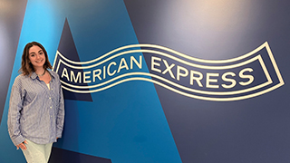 Cristina Hill ‘20 standing by the American Express logo.