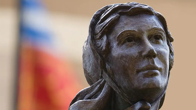 Image of the Mother Seton statue on campus with the flag behind her. 