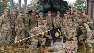 A group of ROTC Cadets with a tank in the background.