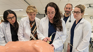 a group of nursing students practicing on a doll